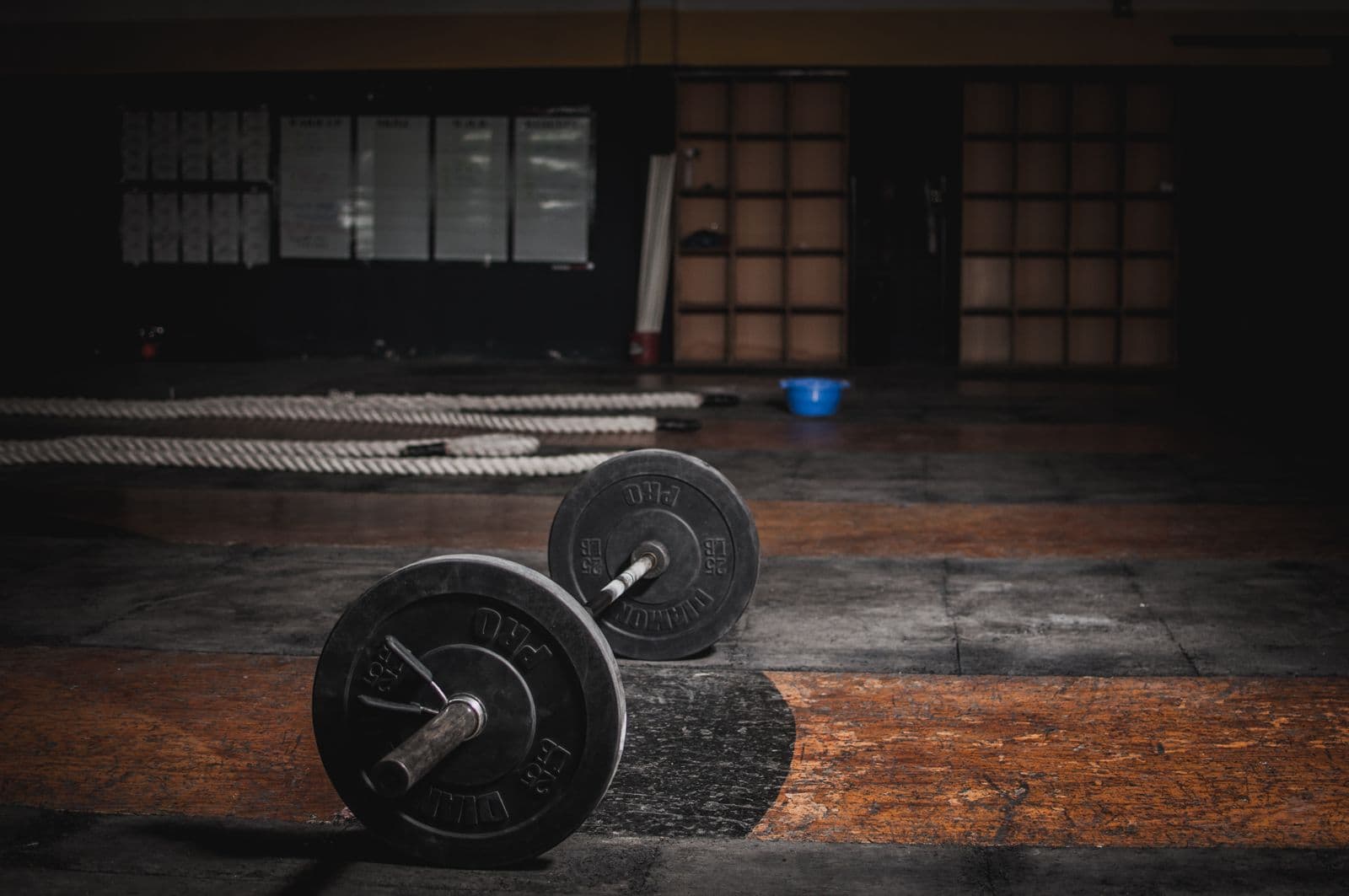 A loaded barbell resting on the floor of a dimly lit gym